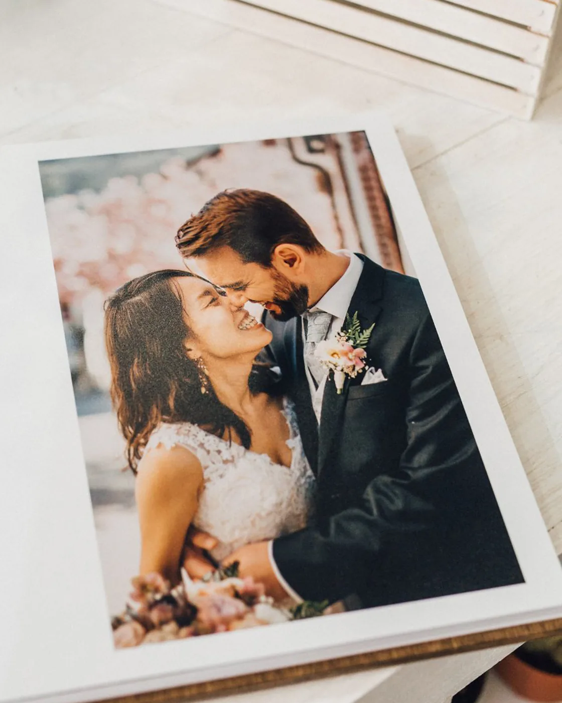 Open wedding photobook with a wooden cover: a full-page photo of the couple laughing